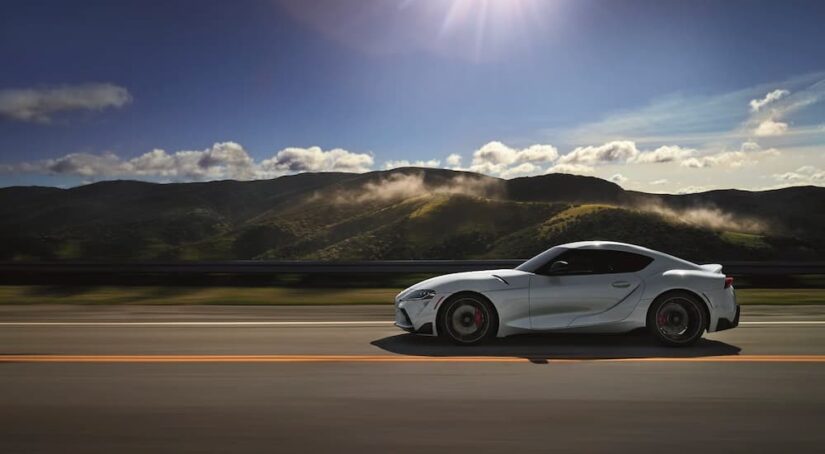 A white 2020 Toyota Supra GR is shown driving on a scenic highway.