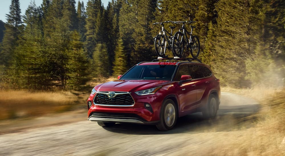 A red 2023 Toyota Highlander is shown from the front at an angle on a dirt road.