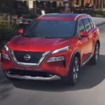 A red 2023 Nissan Rogue is shown driving after competing in a 2023 Nissan Rogue vs the 2023 Mitsubishi Eclipse Cross comparison.