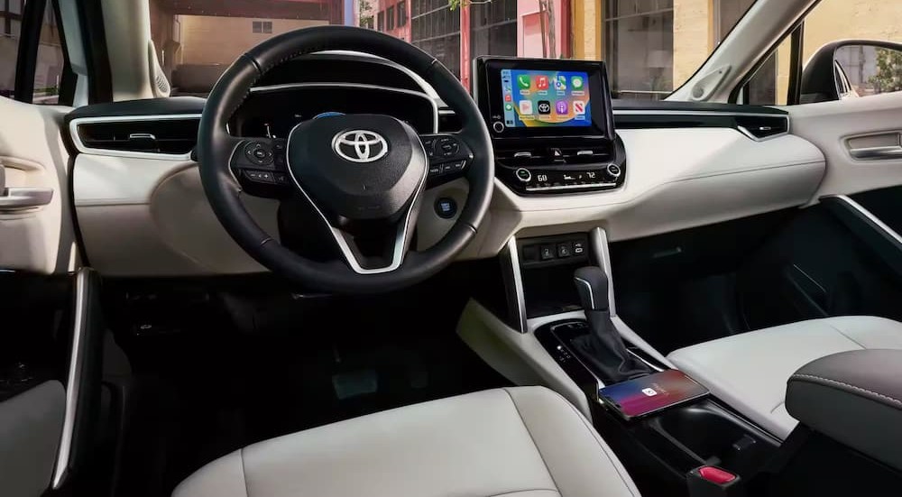 The black and white interior and dash of a 2023 Toyota Corolla Cross Hybrid is shown.