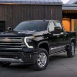 A black 2024 Chevy Silverado 1500 HD High Country is shown parked on a driveway.