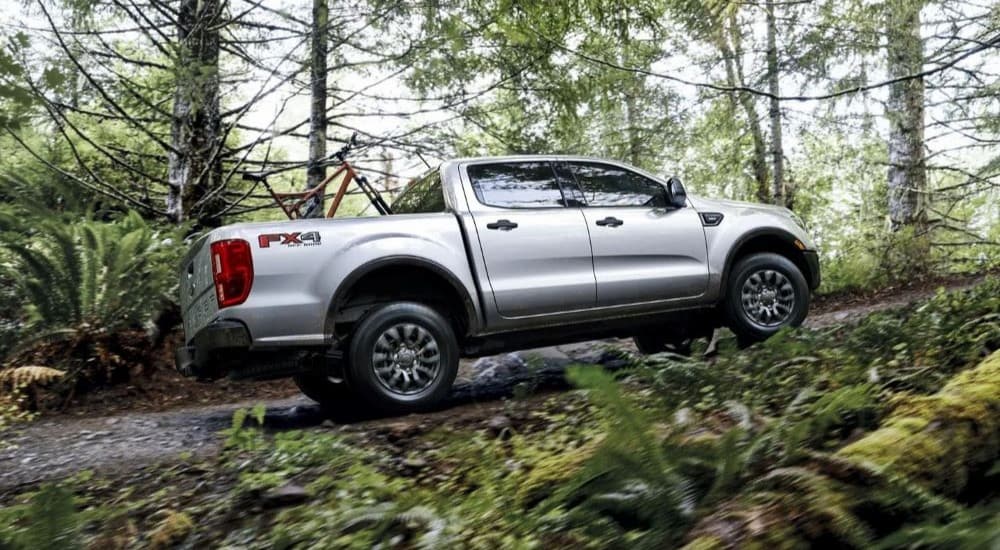 A silver 2023 Ford Ranger XLT FX4 is shown off-roading on a forest road.