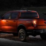 An orange 2024 Ford Ranger Sport 4X4 is shown parked off-road near a Ford dealer.