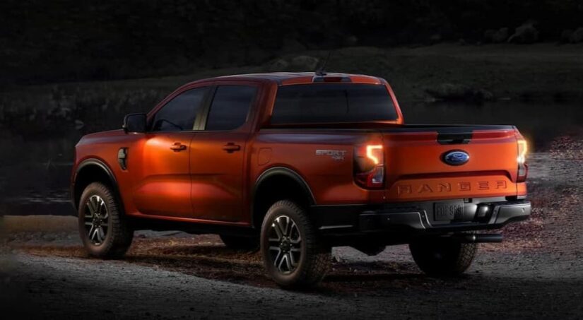An orange 2024 Ford Ranger Sport 4X4 is shown parked off-road near a Ford dealer.