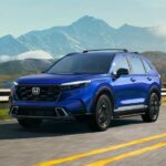 A 2024 Honda CR-V Sport Touring Hybrid is shown driving near a mountain.