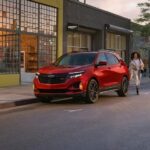 A red 2024 Chevy Equinox RS is shown parked on a city street.