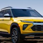 A yellow 2024 Chevy Trailblazer is shown parked near a lake.