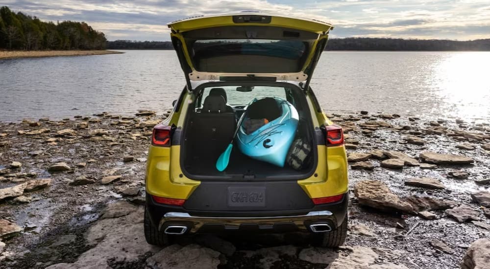 The cargo space of a yellow 2024 Chevy Trailblazer is shown parked near a lake.