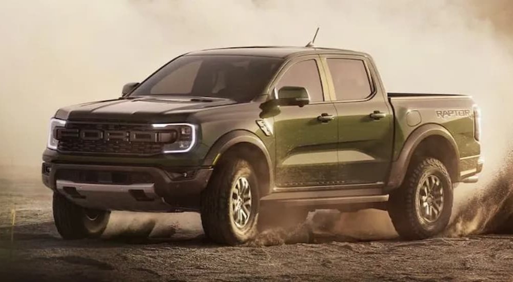 A green 2024 Ford Ranger Raptor is shown driving off-road on sand.