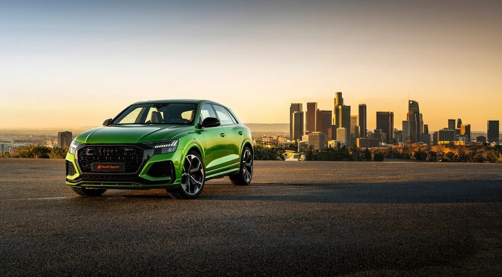 A green 2019 Audi RS Q8 is shown parked near a city.