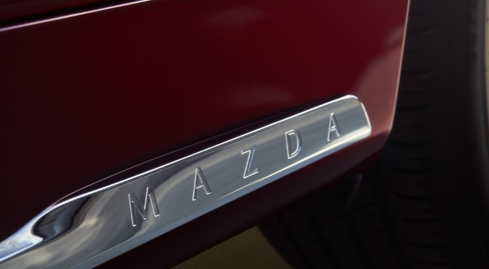 A close up shows the chrome side skirt on a maroon 2024 Mazda CX-90.