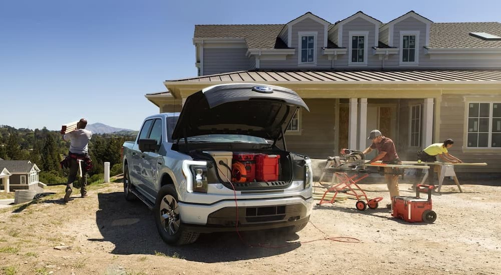 A white 2023 Ford F-150 Lightning is shown parked near a house.