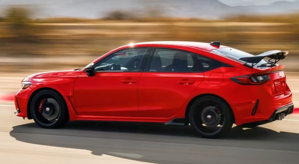 A red 2023 Honda Civic Type-R is shown driving on a racetrack. 