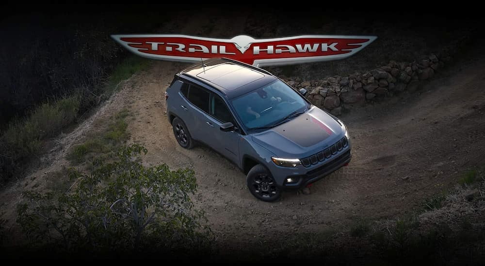 A gray 2023 Jeep Compass Trailhawk is shown parked on a corner of an off-road path.