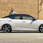 A white 2023 Nissan Sentra for sale is shown parked near a building.