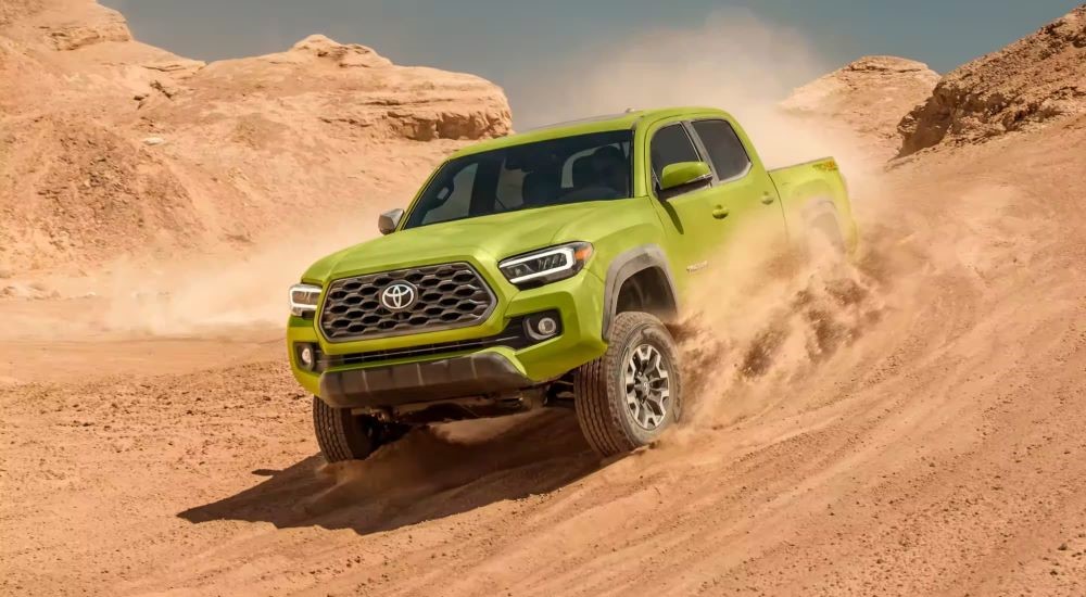 A green 2021 Toyota Tacoma TRD is shown kicking up dust.
