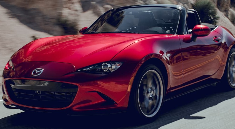 A red 2019 Mazda MX-5 Miata is shown driving on a road.