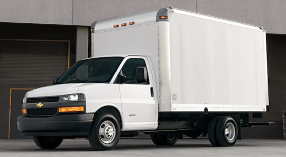 A white 2022 Chevy Express Cutaway is shown parked near a warehouse.