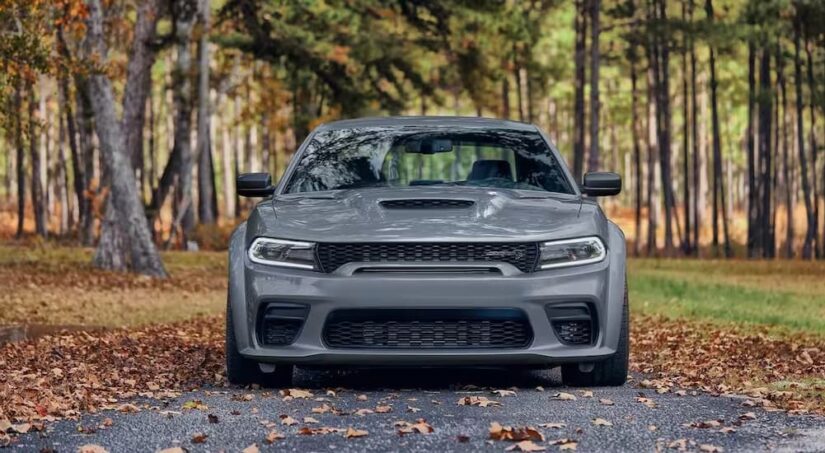 A gray 2024 Dodge Charger SRT Hellcat Redeye, is shown parked near a wooded area.