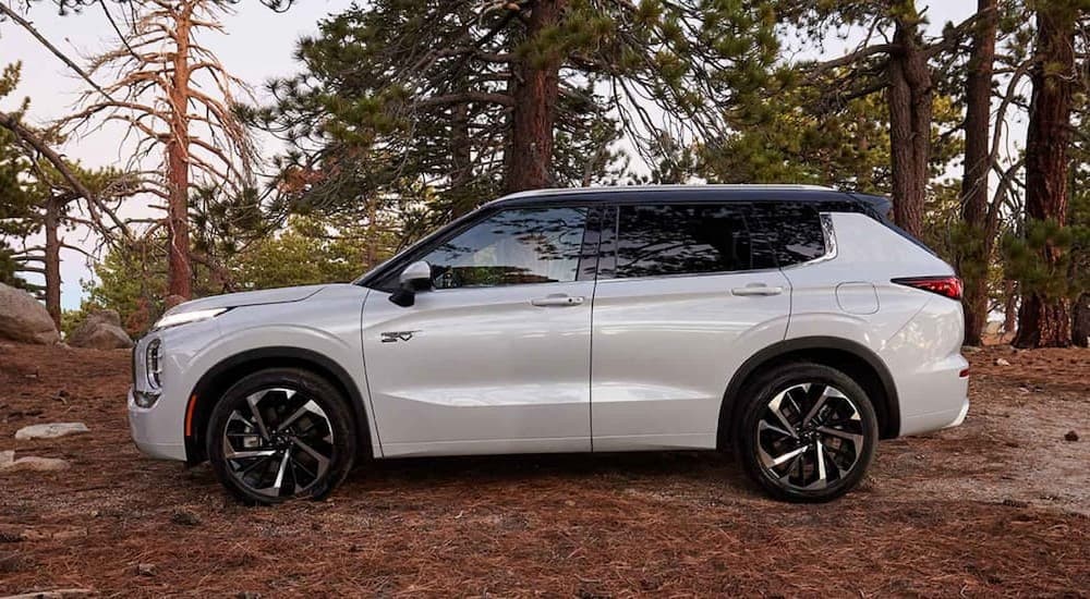 A white 2023 Mitsubishi Outlander PHEV is shown parked off-road.