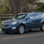 A popular used Chevy Equinox for sale, a blue 2016 Chevy Equinox is shown driving on a road.