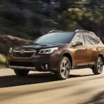 A popular used Subaru for sale, a brown 2022 Subaru Outback Touring, is shown driving on a road.