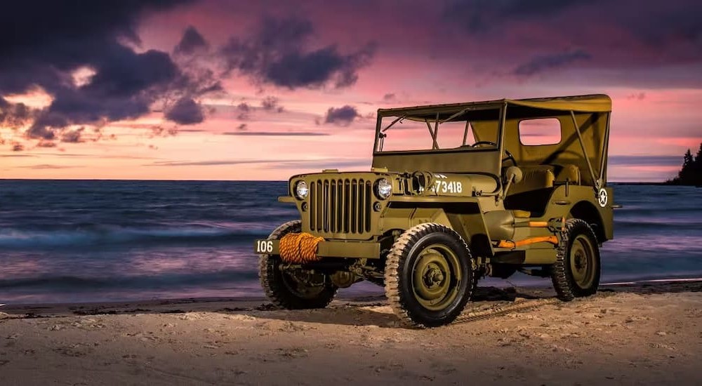 A green 1945 Jeep Willys MB is shown parked on the sand.