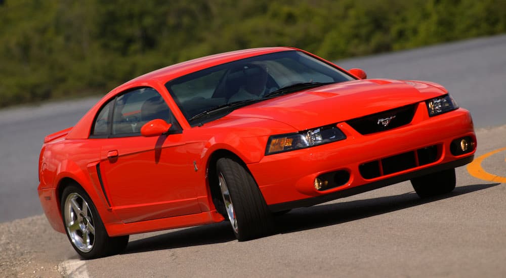 A red 2004 Ford SVT Mustang Cobra is shown driving down a road.