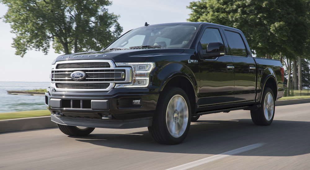 A black 2015 Ford F-150 Limited is shown driving down a road.