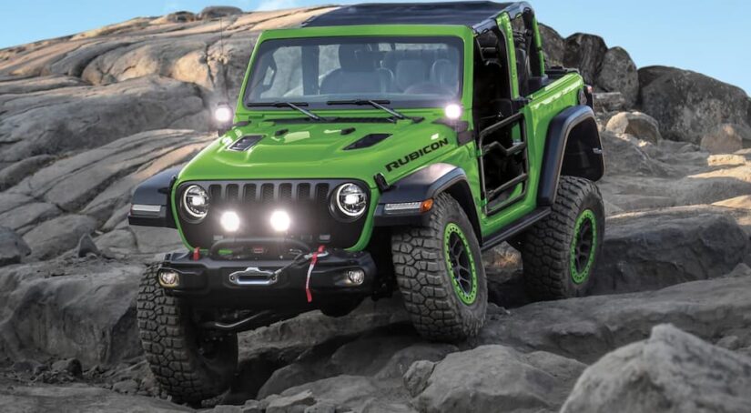 A green 2018 Jeep Wrangler Rubicon JL is shown off-roading after visiting a used Jeep for sale.