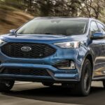 A blue 2020 Ford Edge ST is shown driving on a highway after visiting a Ford dealer.