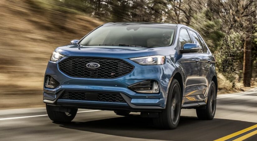 A blue 2020 Ford Edge ST is shown driving on a highway after visiting a Ford dealer.