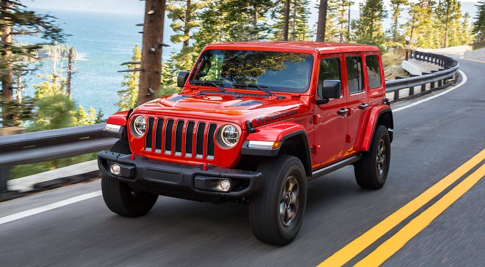 A red 2021 Jeep Wrangler Rubicon is shown driving on a highway.