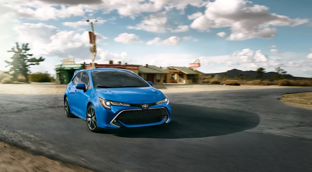 One of the safest used cars, a blue 2022 Toyota Corolla, is shown driving near a motel.