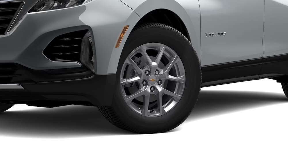 The wheel and door badge of a silver 2023 Chevy Equinox LT is shown.
