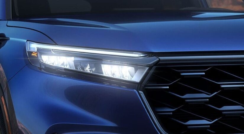 A close-up on the headlight of a blue 2023 Honda CR-V Hybrid for sale.