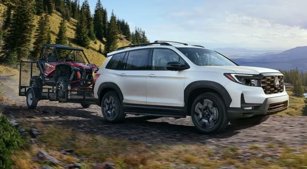 A white 2023 Honda Passport is shown towing a trailer.