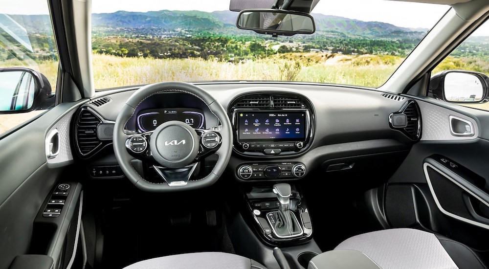 The black interior of a 2023 Kia Soul, including the wheel and dashboard, is shown.