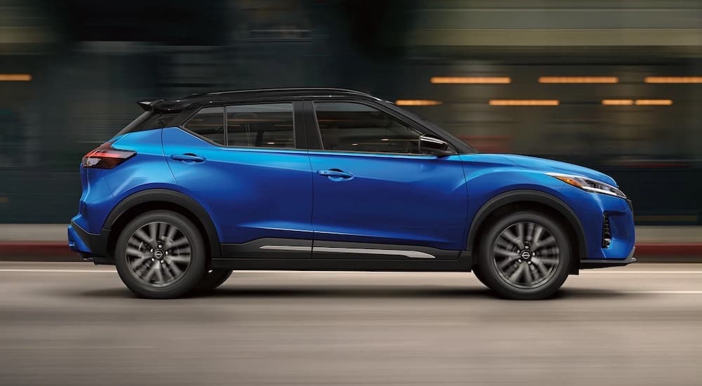 A blue 2023 Nissan Kicks is shown from the side driving through a tunnel.