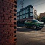 A green 2023 Toyota Highlander Hybrid for sale is shown parked near a brick wall.