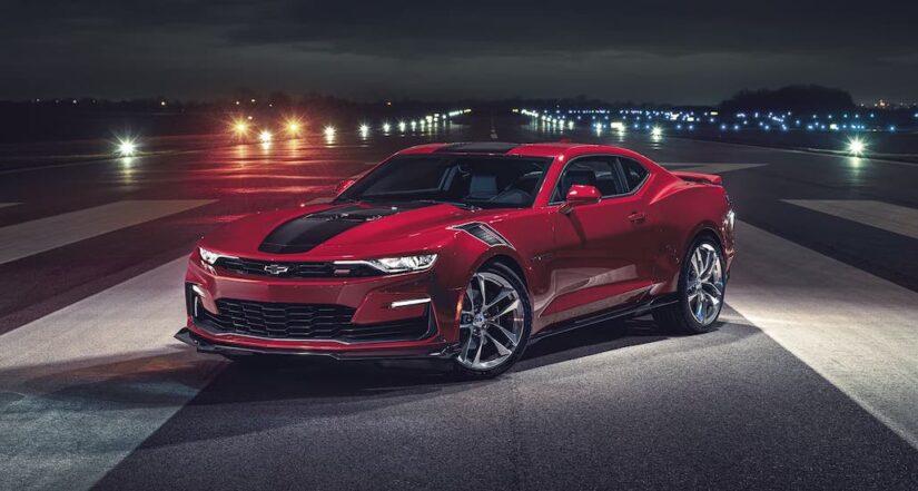 A red 2024 Chevy Camaro is shown parked on a runway at night.