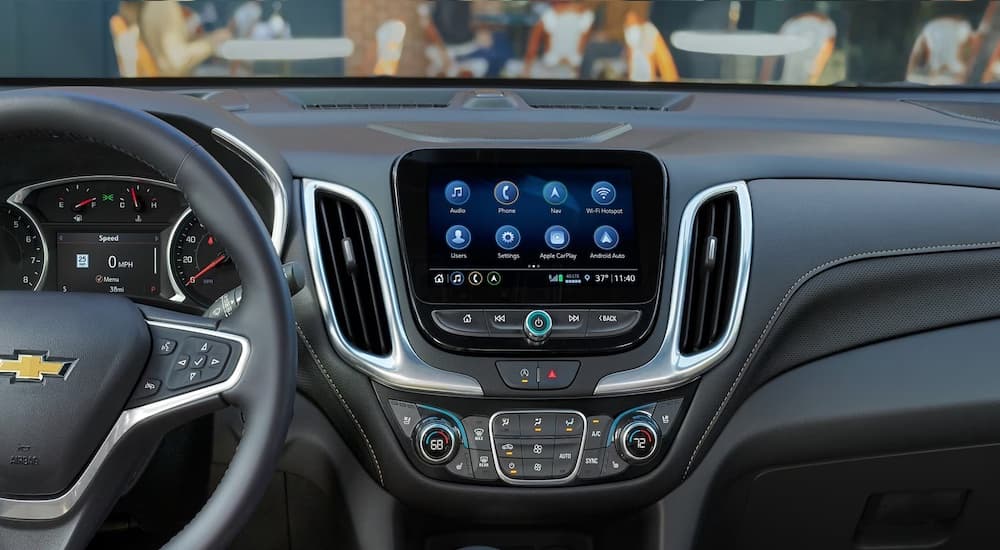 The black interior and dash of a 2024 Chevy Equinox is shown, including the gauges, dashboard and steering wheel.