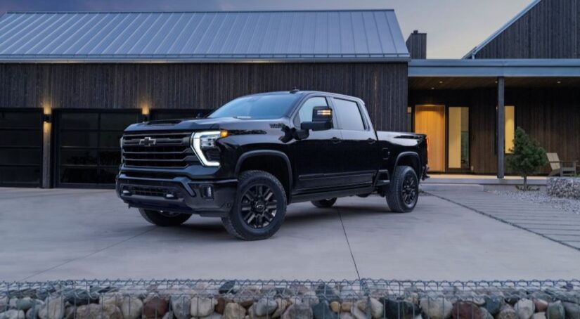 A black 2024 Chevy Silverado 2500 HD High Country is shown parked near a Chevy dealer.