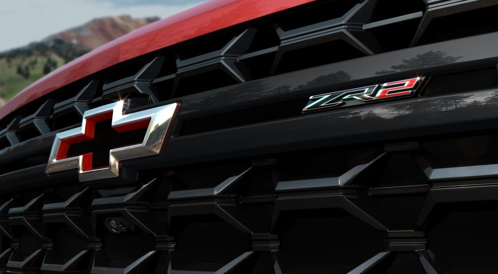 A close-up on the front grille of a red 2024 Chevy Silverado 2500 HD ZR2 is shown.