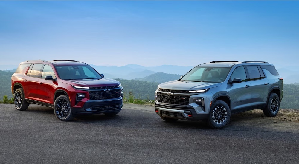 A pair of 2024 Chevy Traverse, one red and the other gray.