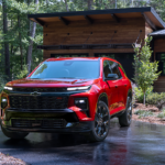 A red 2024 Chevy Traverse RS is shown parked near a house.