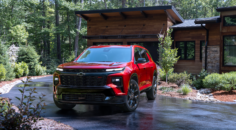 A red 2024 Chevy Traverse RS is shown parked near a house.