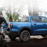 A blue 2024 Ford Ranger Sport is shown parked near a person on a bicycle.