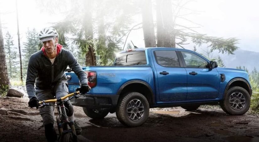 A blue 2024 Ford Ranger Sport is shown parked near a person on a bicycle.