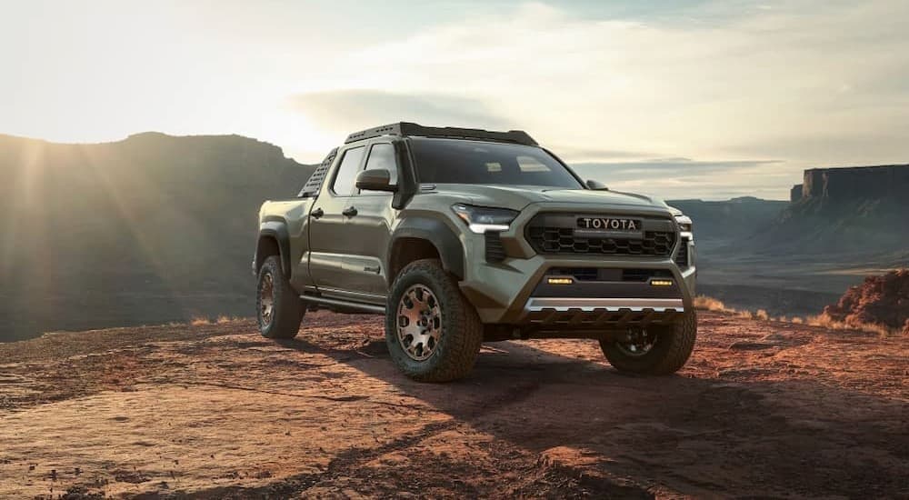 A green 2024 Toyota Tacoma is shown parked off-road on dirt.